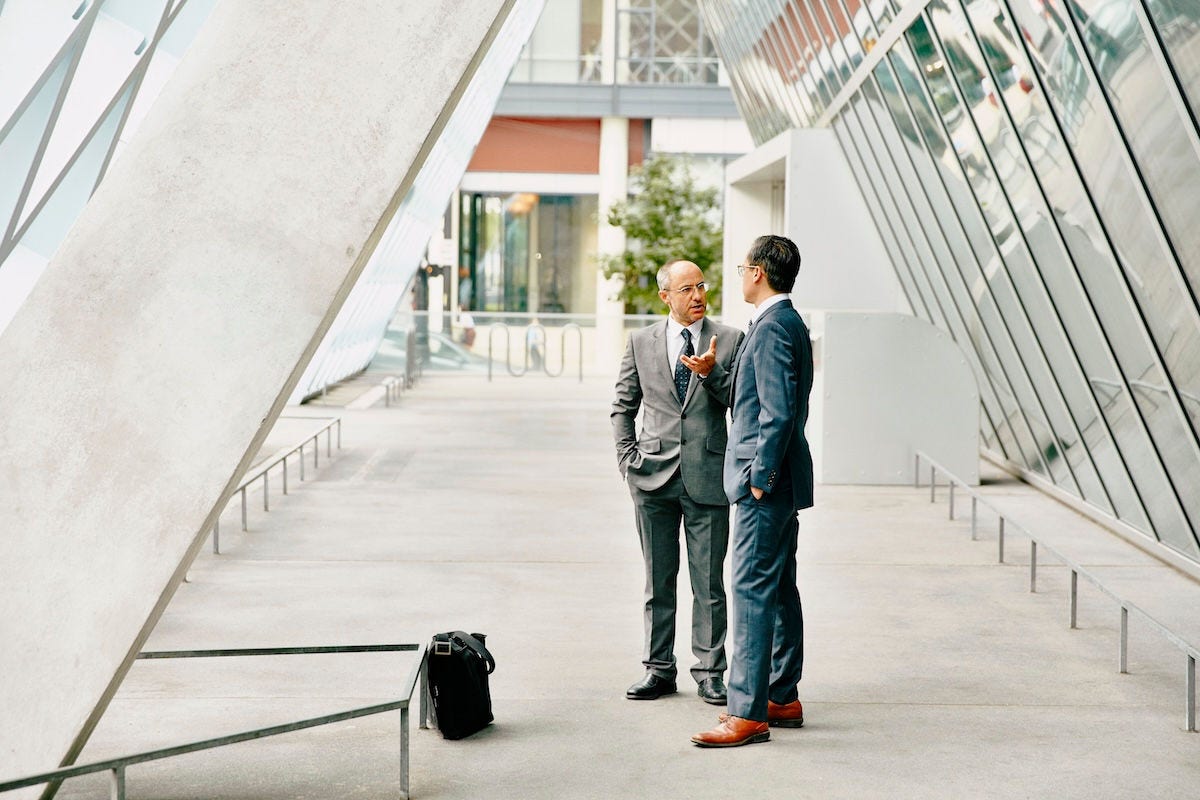 Businessman in discussion with colleague in outdoor corridor of office building