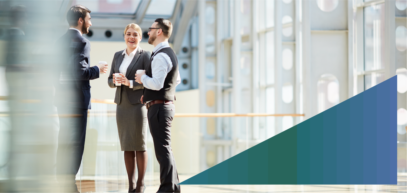 photo of a group of young business colleagues standing in a hallway and having a conversation during a coffee break.