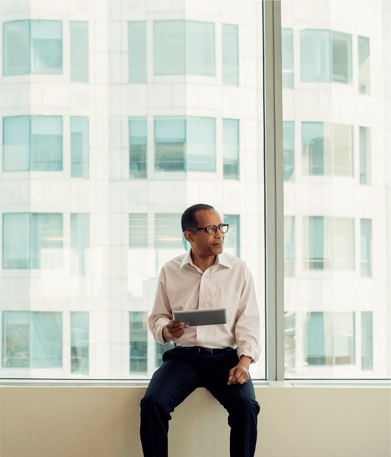 Businessman sitting on window sill with iPad
