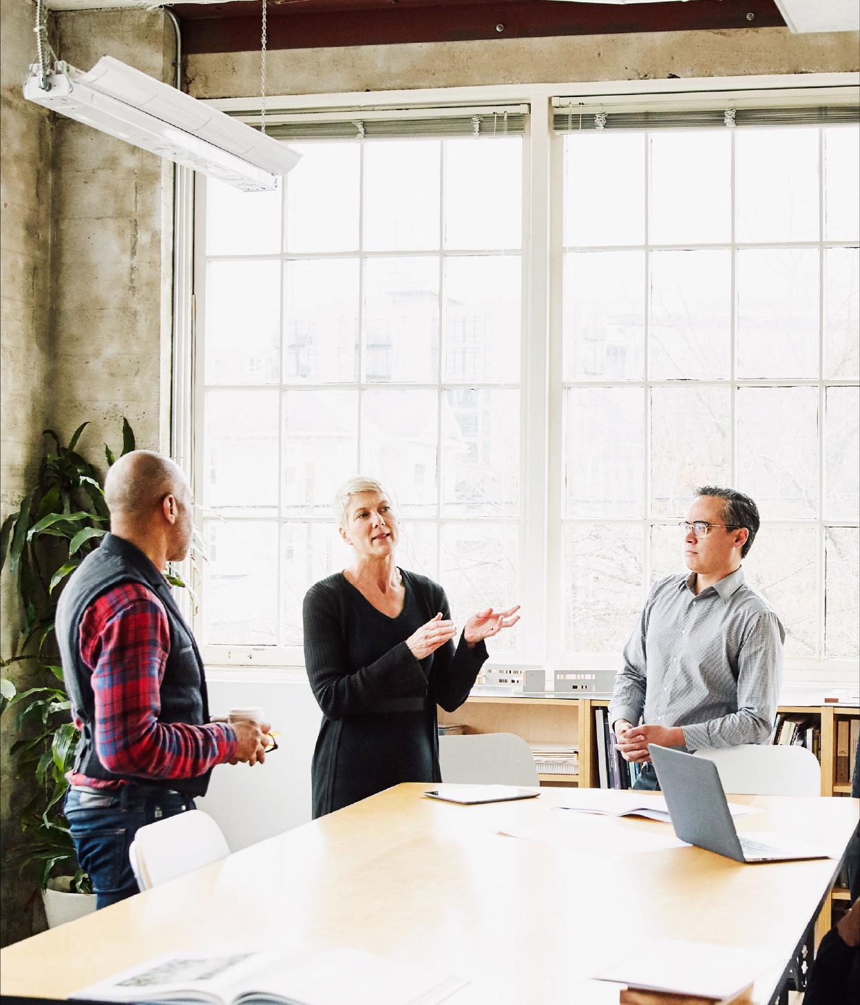 Three office employees hold a discussion in a conference room.