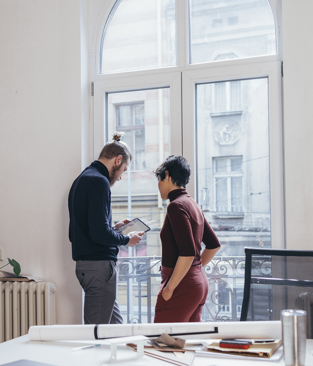 Dos compañeros de trabajo de pie junto a una ventana.